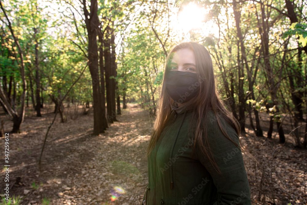 a young girl of European appearance in a medical mask on nature. infection protection. quarantined walks in the park. bright highlights. a young girl of European appearance in a medical mask on nature. infection protection. quarantined walks in the park. bright highlights.