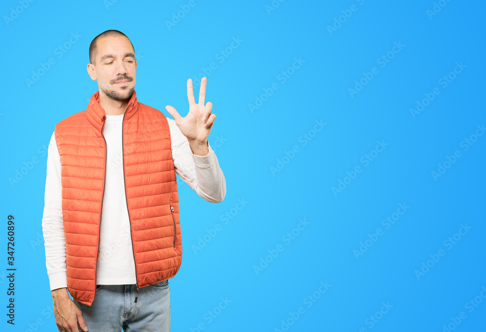 Young man making a number three gesture