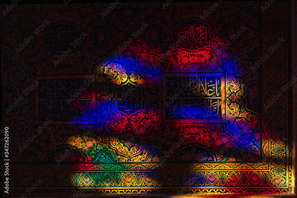 Nasir-ol-molk Mosque is full of colorful light in the morning. A wall is painted in colorful colors from light through stained glass. Shiraz, Iran.