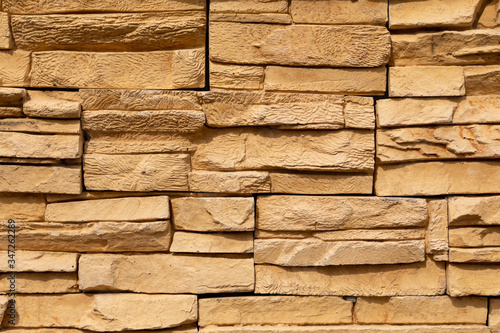 Texture of the yellow surface of a slate stone. Blocks of natural finishing stone for wall decoration. Rough stone background.