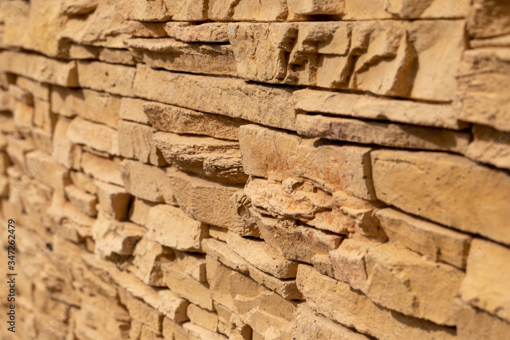 Blurred background of yellow slate stone surface. Blocks of artificial finishing stone for wall decoration. Rough stone background. Blurred background of yellow slate stone surface. Blocks of artificial finishing stone for wall decoration. Rough stone background.