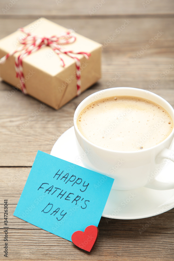 Fathers Day message with coffee cup and gift on grey wooden background Fathers Day message with coffee cup and gift on grey wooden background