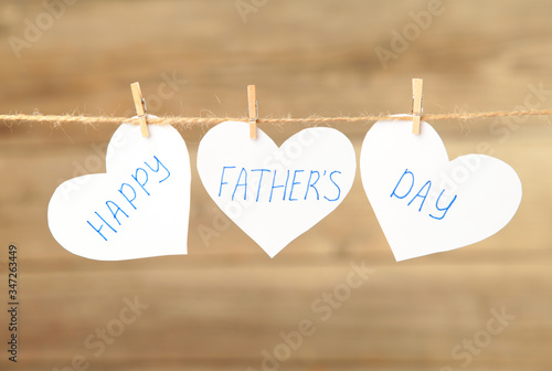 Happy Fathers Day written on paper hearts on grey background