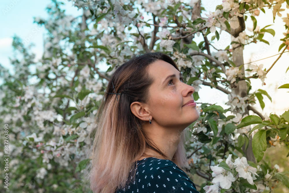 Dreamy young woman among blooming garden ooking at the right upper corner Dreamy young woman among blooming garden ooking at the right upper corner