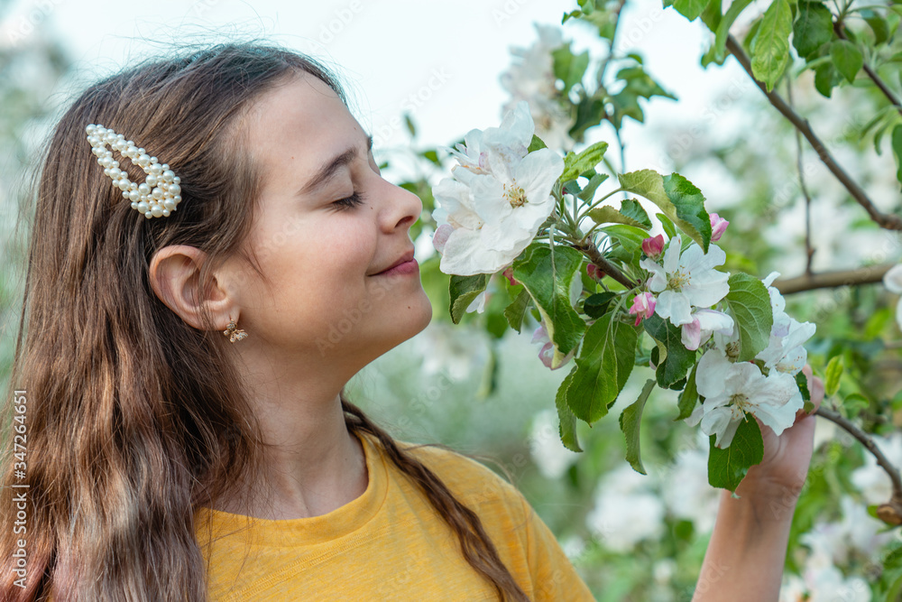 Tender brunette girl with natural makeup smelling blooming branch with closed eyes Tender brunette girl with natural makeup smelling blooming branch with closed eyes