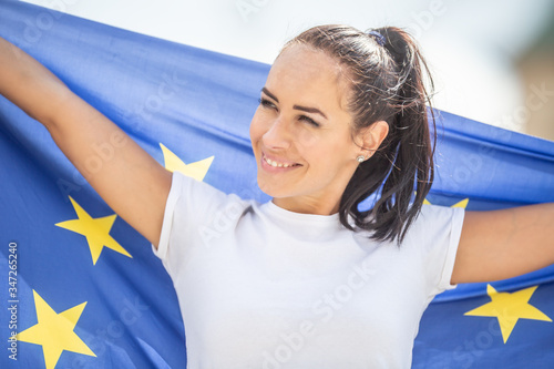 Smiling beautiful woman holding an EU flag looking to the side