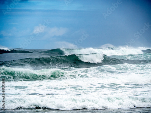 Big waves on the north shore of Oahu with aquamarine seas  white foam and blue skies.