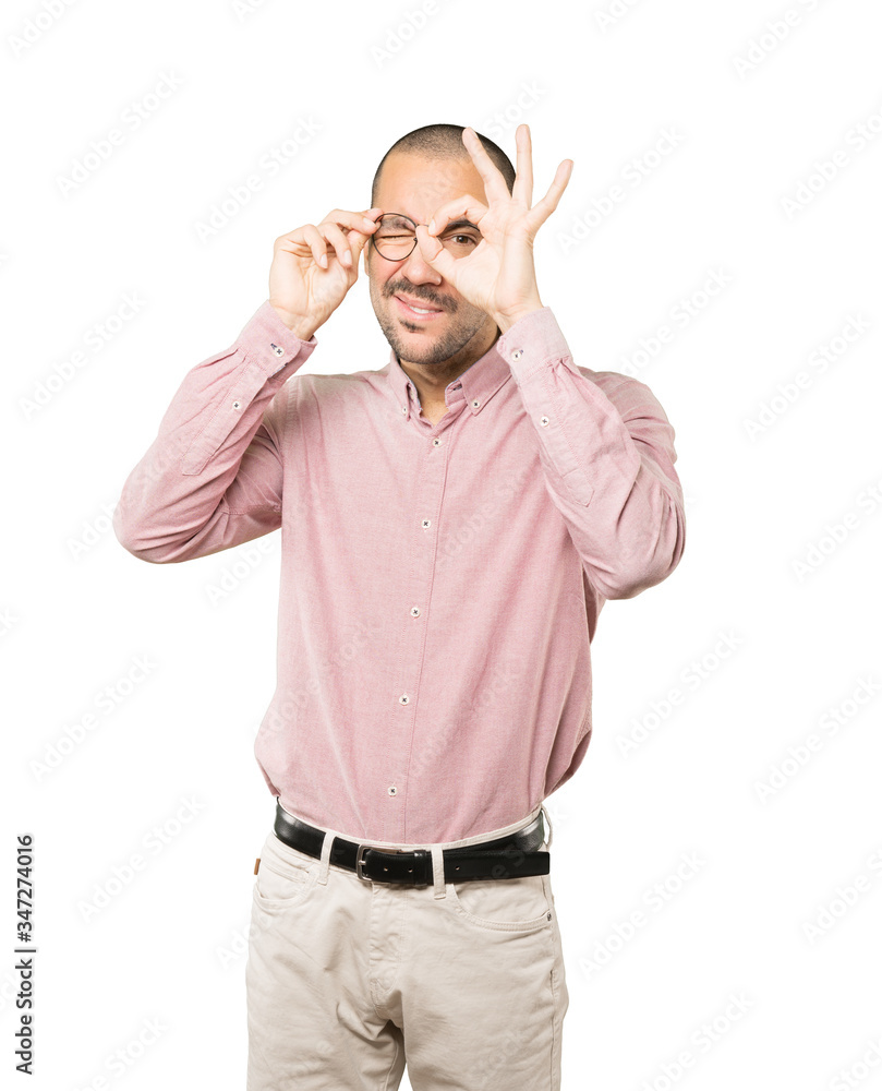 Happy young man using his hands like a binoculars Happy young man using his hands like a binoculars
