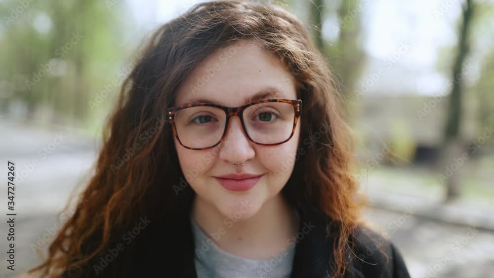 Red-haired girl in glasses looking at the camera and smiling. Red-haired girl in glasses looking at the camera and smiling.