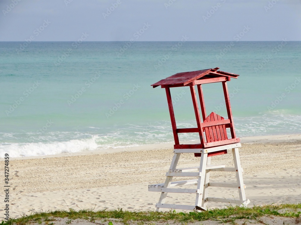 Imagen de una caseta inclinada de madera para los vigilantes de la playa en color blanco y rojo en el Mar Caribe