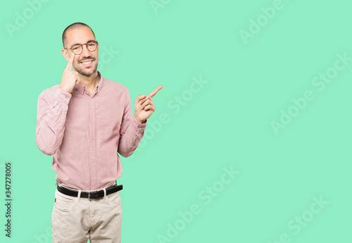 Friendly young man making a gesture of being careful with his hand pointing at his eye