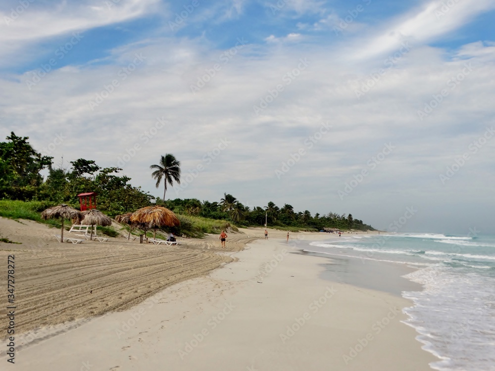 Fotografía del la Playa de Varadero, Cuba con las aguas azules del Mar Caribe y la arena blanca bajo un cielo azul con nubes blancas