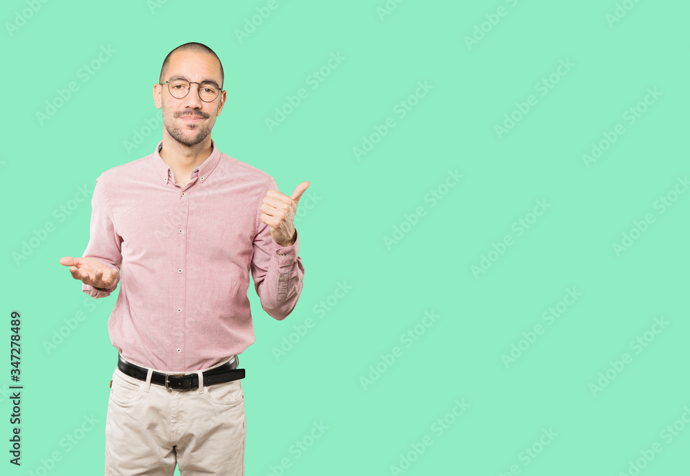 Hesitant young man gesturing that everything is fine Hesitant young man gesturing that everything is fine