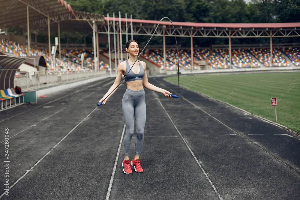Beautiful girl at the stadium. Sports girl in a sportswear. Lady with jump rope