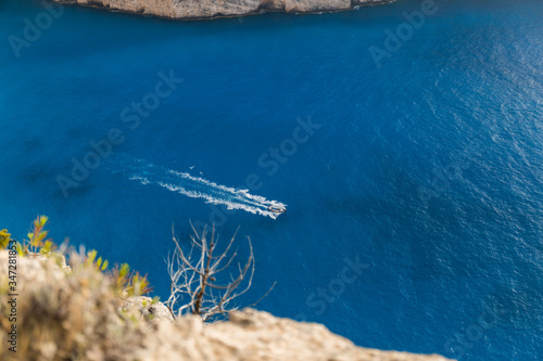 speedboat rides the deep blue sea near the beautiful Navagio beach on the island of Zakynthos in Greece