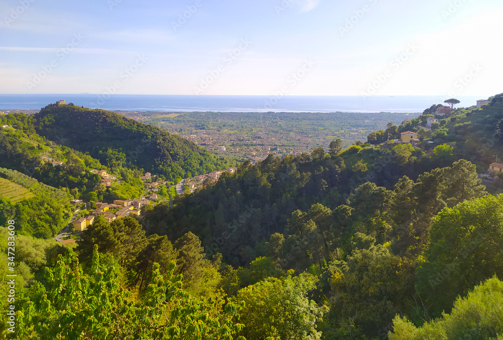 panoramic view of the Apuan Alps between the green mountains and the blue sea between the lush hills