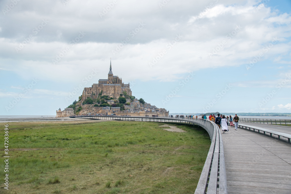 People taking the raised boardwalk to Mont Saint-Michel in Normandy, France