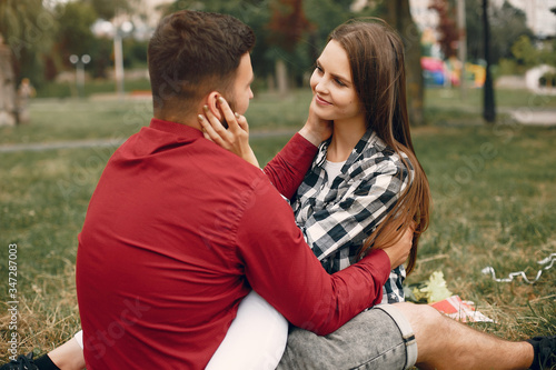 Cute couple in a park. Pair sitting on a blanket. Guy in a red shirt