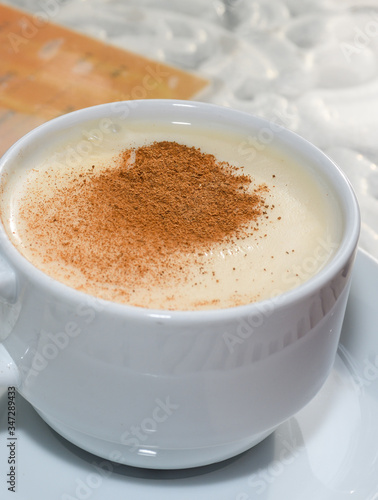 white cup of salep milky hot drink of Turkey with cinnamon powder and sticks healthy spice