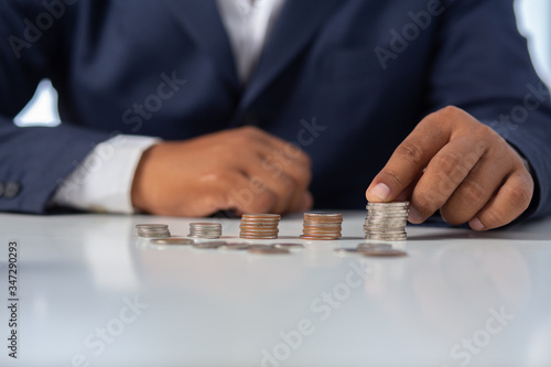 Businessman hand with putting money coins a desk in the office.concept: Saving money wealth and financial Personal, finance management loan for a home, diagram chart earnings to plan profit