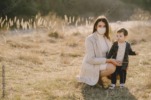 Family in a autumn field. Mother in a white sweater. Cute little son. Coronavirus theme. photo