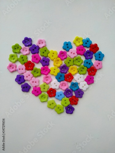 many colorful buttons in the shape of a flower laid out in the shape of a heart isolated on a white background 
