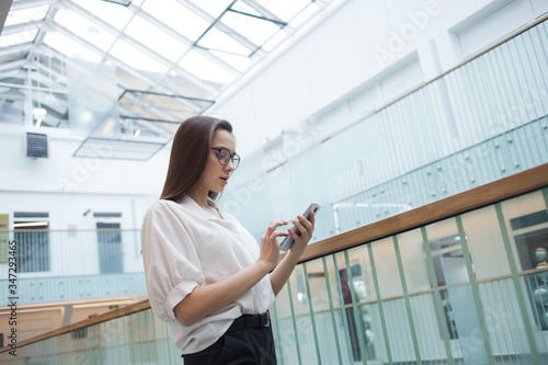 young positive business woman in glasses and a white shirt communicates in a messenger