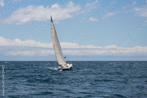 A sailing boat navigating in front of Barcelona coast line during a stormy winter afternoon.