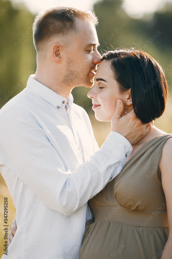 Pragnant woman. Family in a field. Man in a white shirt Pragnant woman. Family in a field. Man in a white shirt