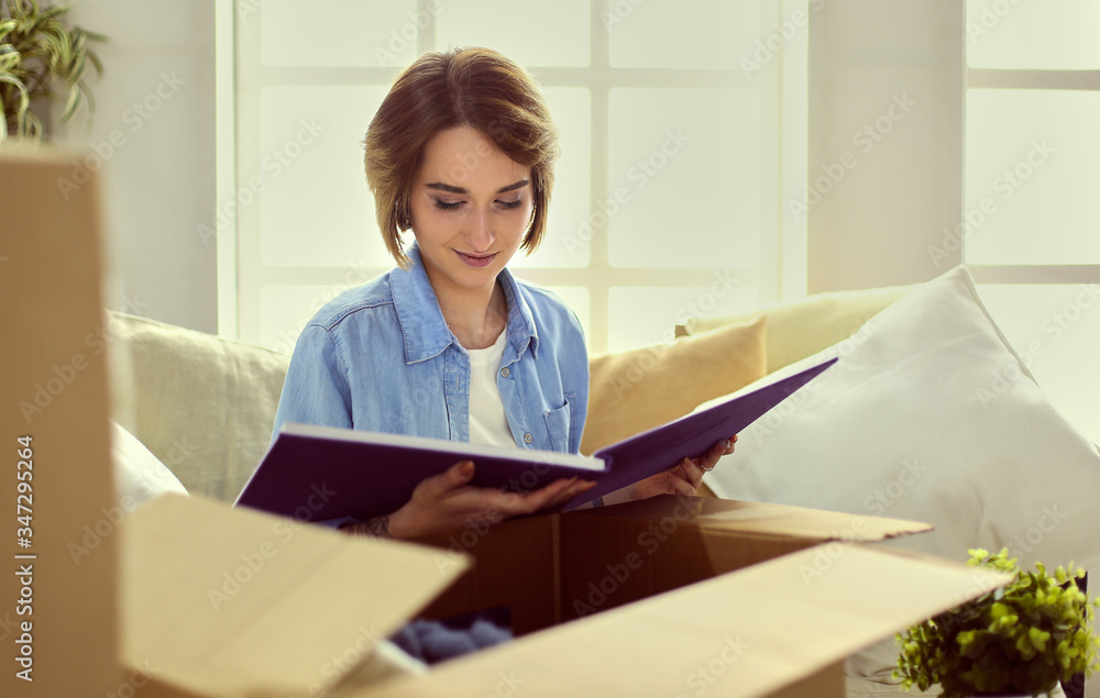 Young woman moving out and packing cardboard box Young woman moving out and packing cardboard box
