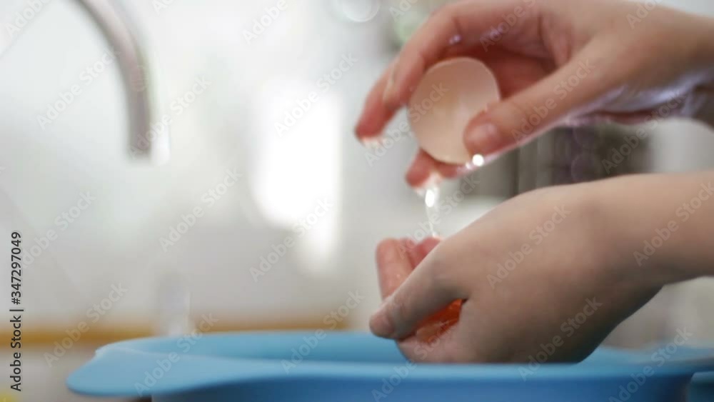 Woman's hands separating the egg white from the egg yolk with her hands Woman's hands separating the egg white from the egg yolk with her hands