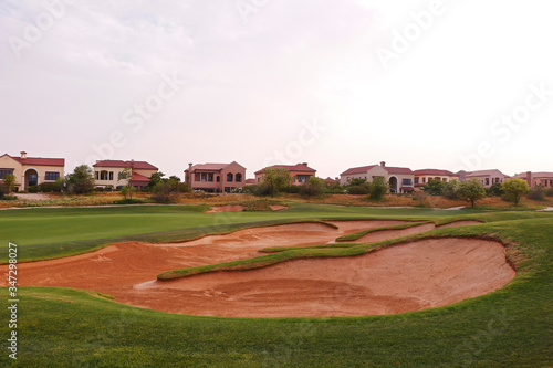 golf course and bunkers in a sunny day with background of italian model villas