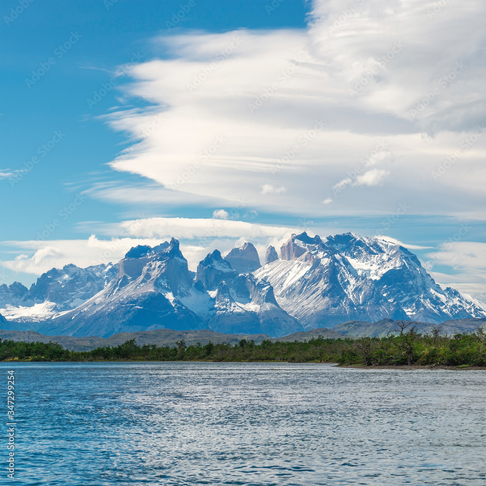 The Torres and Cuernos del Paine peaks seen from the Serrano River with circular clouds, Torres del Paine national park, Patagonia, Chile.