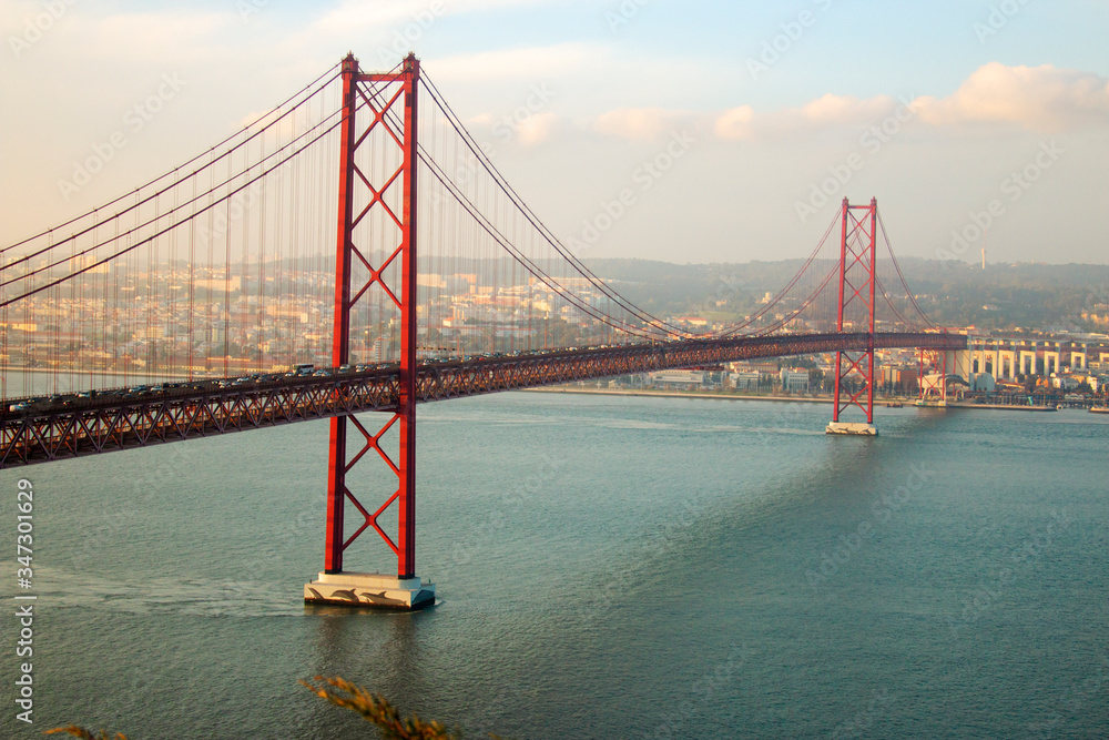 Obraz premium View of 25th of April Bridge, a suspension bridge connecting the city of Lisbon, capital of Portugal, to the municipality of Almada on the left (south) bank of the Tagus river. Lisbon, Portugal