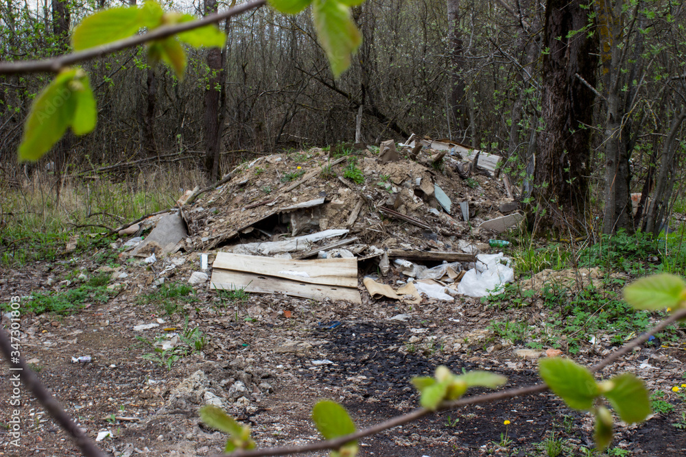 Garbage dump in the forest near the road. View through branches and leaves Garbage dump in the forest near the road. View through branches and leaves