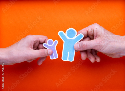 Illustration famille monoparentale, deux mains tenant chacune une illustration d'homme ou de femme et d'enfant avec les bras levés, contents de se retrouver, réconciliation, sur fond orange