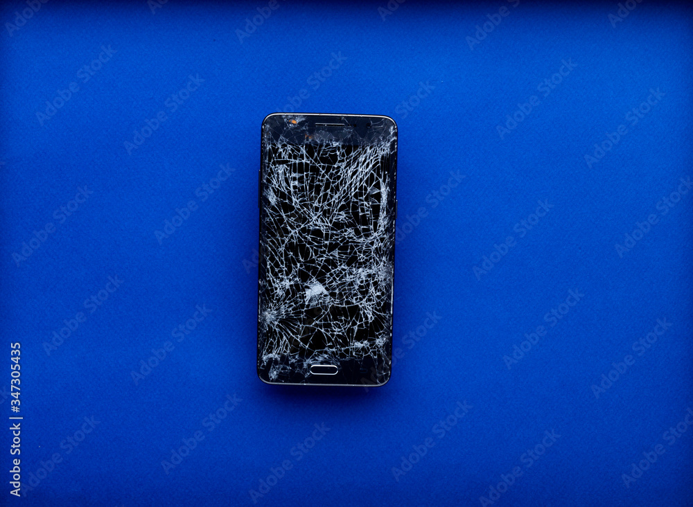 Smartphone écran cassé brisé isolé sur fond bleu Smartphone écran cassé brisé isolé sur fond bleu