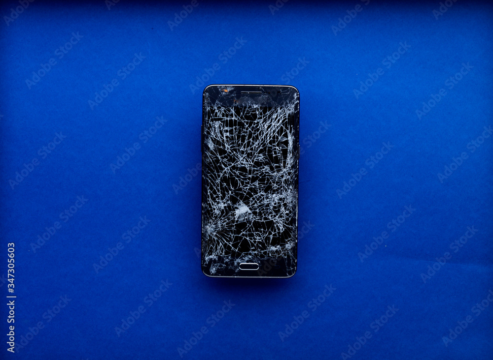 Smartphone écran cassé brisé isolé sur fond bleu Smartphone écran cassé brisé isolé sur fond bleu