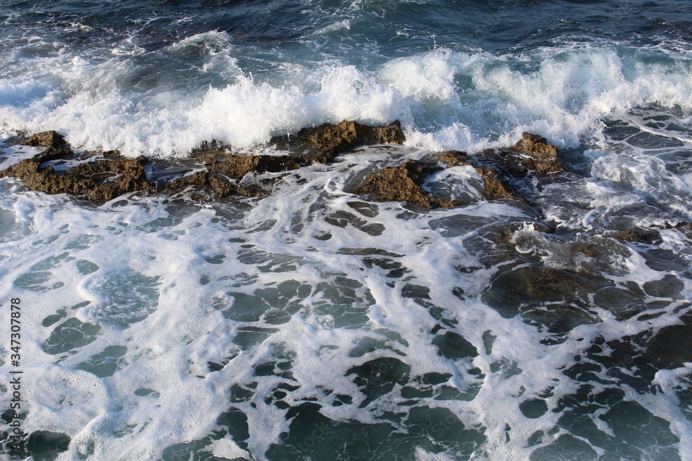 Mediterranean sea waves splashing at the rocks with foam in Chania, Crete Island, Greece.