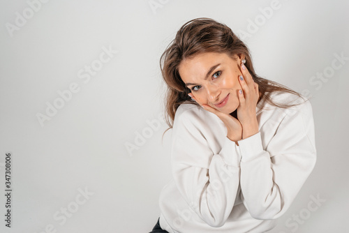 Pretty smiling young woman with arms on her face. Isolated on white background