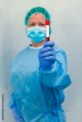 Doctora con protección, máscara y gorro, mostrando un test de sangre.