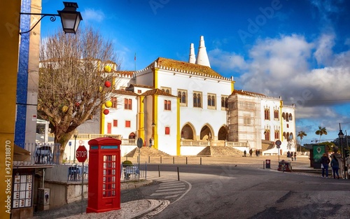 A scenic street view of Sintra, Portugal, with a town palace and a red telephone booth