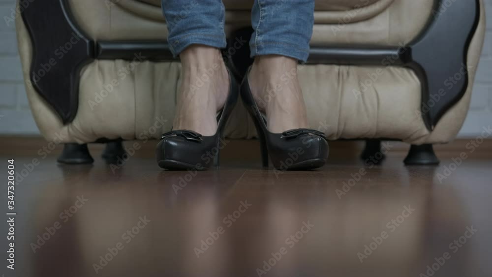 Tired woman's legs. The woman takes off her high-heeled shoes and strokes her tired legs. Tired woman's legs. The woman takes off her high-heeled shoes and strokes her tired legs.