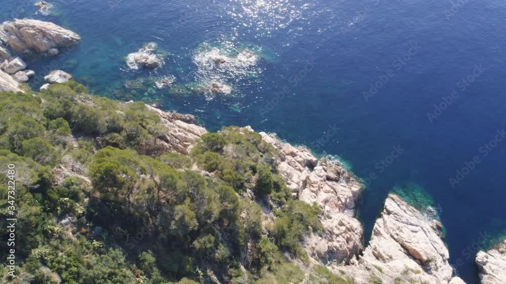 Aerial Drone side close-up view of mediterranean cliff with green trees, rocks and blue water Aerial Drone side close-up view of mediterranean cliff with green trees, rocks and blue water
