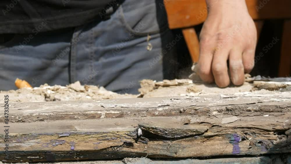 Men's hands dismantle the frames of an old rotten wooden window. Replacing an old window with a new one. Men's hands dismantle the frames of an old rotten wooden window. Replacing an old window with a new one.