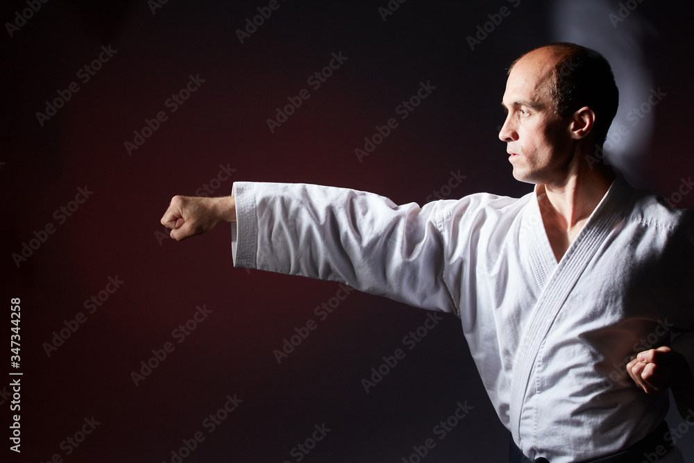 Against a dark red background, a young athlete beats a punch arm Against a dark red background, a young athlete beats a punch arm