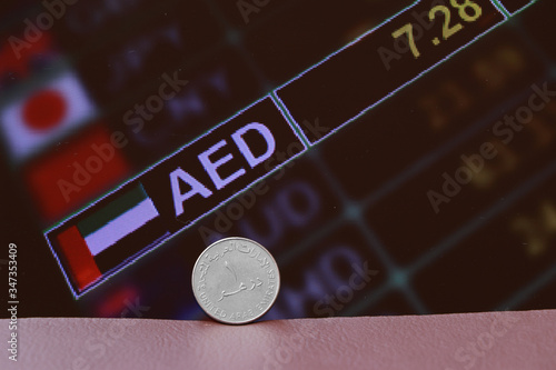 The coin of United Arab Emirates one dirham money on obverse on brown floor with digital board of currency exchange money background.