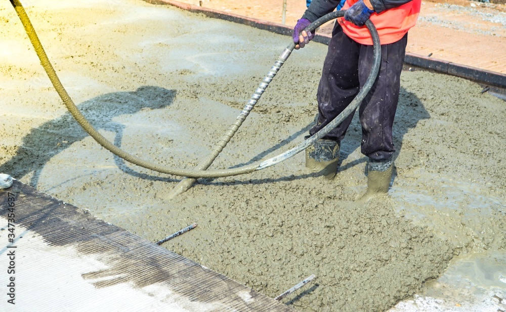 Construction workers using concrete vibrator for concrete density at road pavement construction