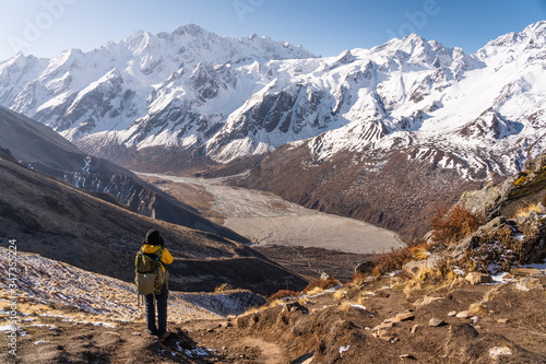A trekker standing on top of Kyanjin Ri view point and taking picture of Langtang mountain range, Himalaya mountains range in Nepal photo
