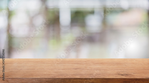 Empty wood table top and blur glass window interior restaurant banner mock up abstract background - can used for display or montage your products.